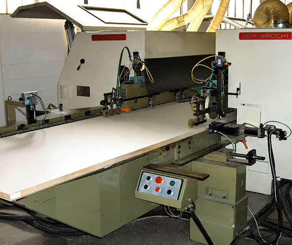 Macchina industriale per lavorazione e taglio con sistema di guida e controllo elettrico, cavi e componenti meccanici in officina, piano di lavoro bianco